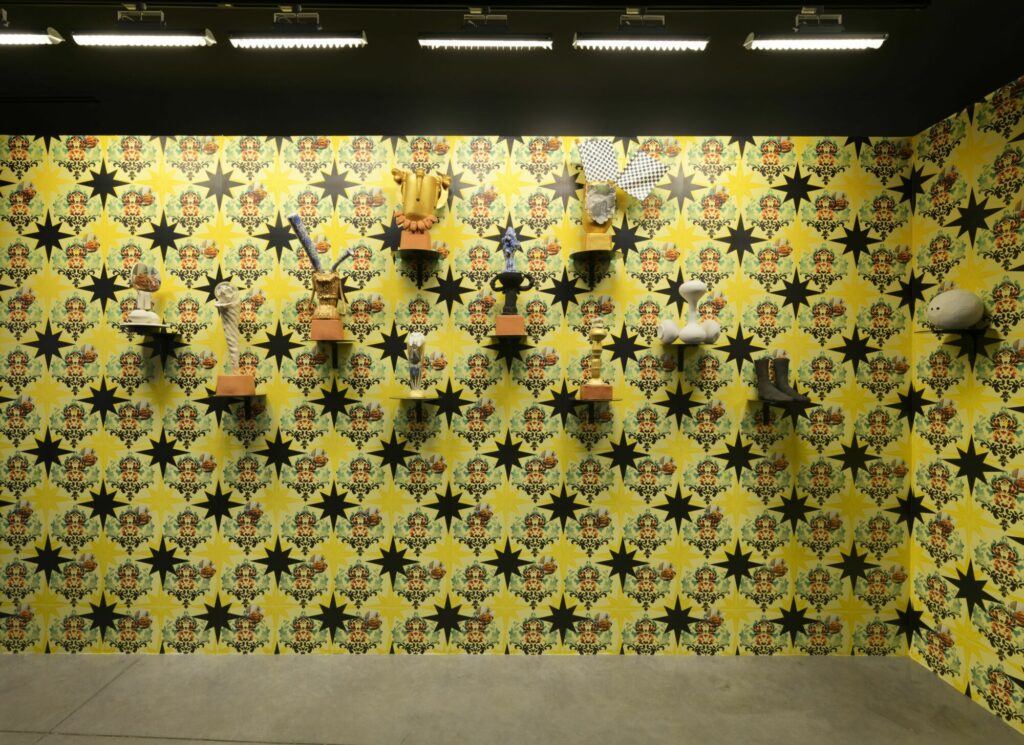 Aurélie Piau, Va y’avoir du sport (de la serie Décor intérieur), 2023, installation mixte (papier peint numérique, raquettes de ping-pong en faïence, sculpture en faïence blanche, présentoir rotatif, tablette en bois, dimensions variables - Collection Frac Occitanie Montpellier. Photo Aurélien Mole